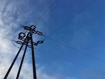 Low angle view of electricity pylon against blue sky