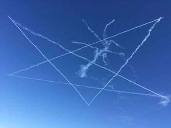 Low angle view of vapor trails against blue sky