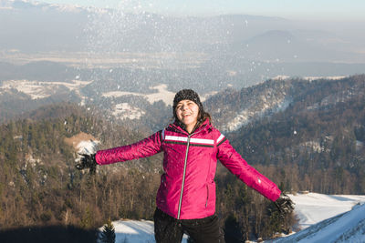 Woman playing with snow against mountains