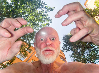 Portrait of man holding plant against trees