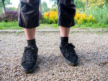 Low section of man standing on pebbles