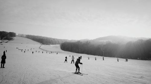 People skiing on snow covered landscape against sky