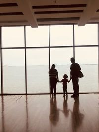 Rear view of people standing by window