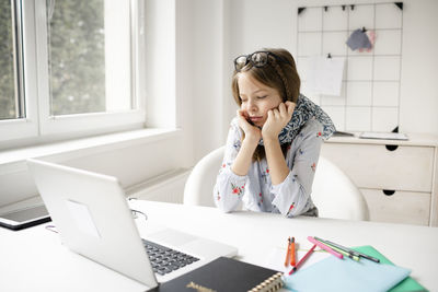 Young woman using mobile phone while sitting at table