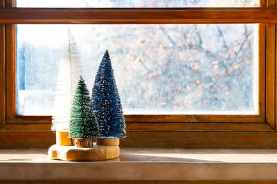 Colourful christmas trees on the window. trendy home decor for winter holidays.