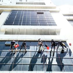 Low angle view of workers cleaning glass windows of building