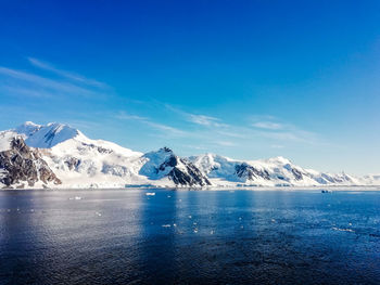 Scenic view of snowcapped mountains against blue sky