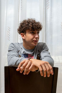 Young man looking away while sitting on seat