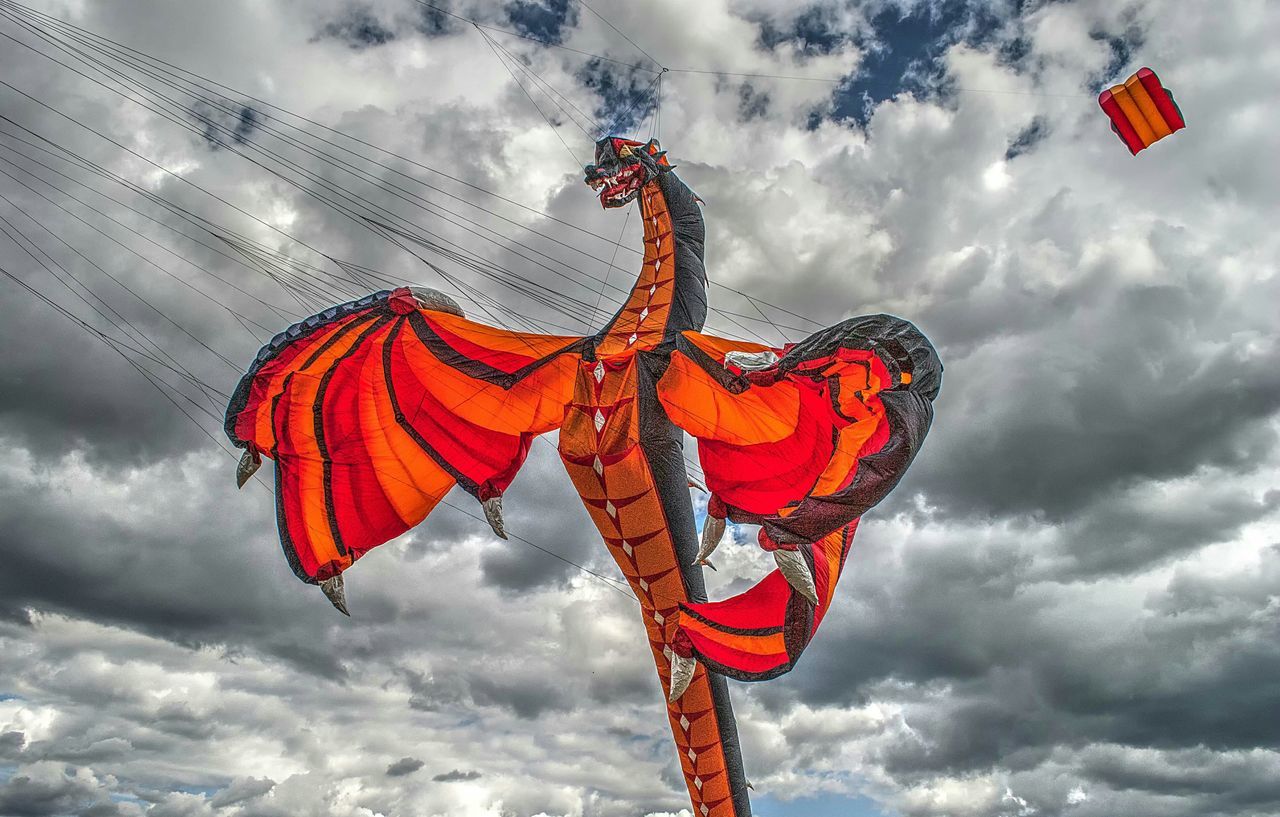 low angle view, sky, cloud - sky, flag, patriotism, national flag, identity, cloudy, red, american flag, cloud, multi colored, wind, pride, hanging, cultures, pole, day, tradition, outdoors