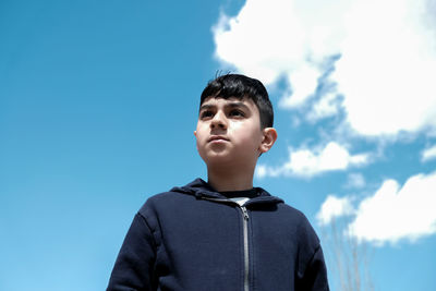 Low angle view of young man standing against blue sky