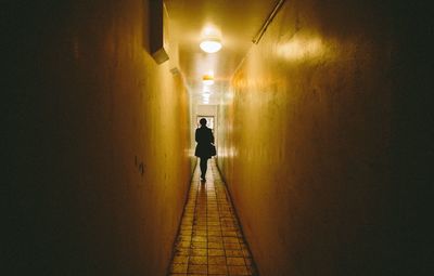 Man standing on illuminated corridor