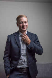 Portrait of young man standing against wall