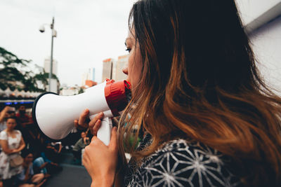 Side view of woman talking on megaphone on city street