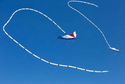 Low angle view of kite flying against clear blue sky