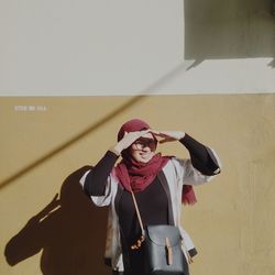 Portrait of smiling young woman standing against wall