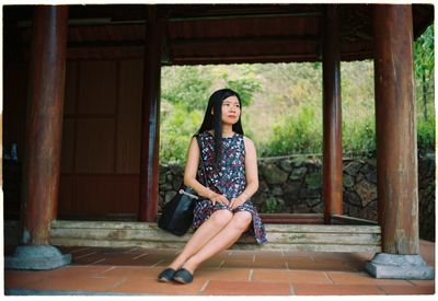 Portrait of woman sitting against brick wall