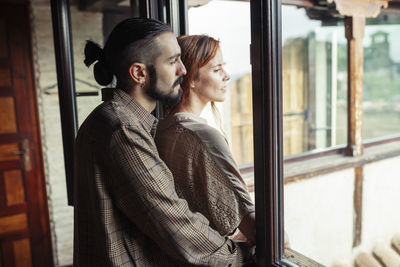 Man and woman standing by window at home