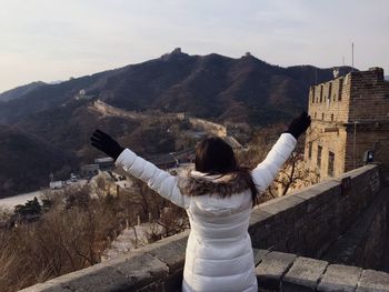 Rear view of woman with arms outstretched standing against great wall of china