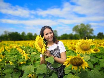 Portrait of a smiling young woman in sunflower field