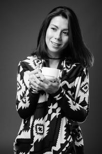 Portrait of smiling young woman drinking coffee