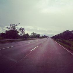 Empty road with trees in background