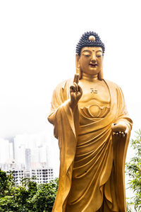 Statue of buddha against building against sky