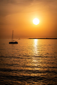 Silhouette sailboat in sea against sky during sunset