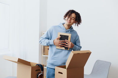 Portrait of smiling young woman holding box