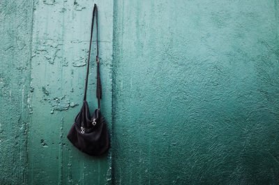 Black shoulder bag hanging from nail mounted on wall