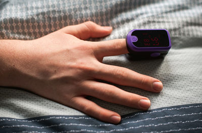 Close up of a hand with a pulse oximeter on the finger.