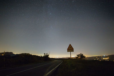 Road sign against sky at night