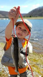 Portrait of boy holding string with fish at riverbank in lyman run state park