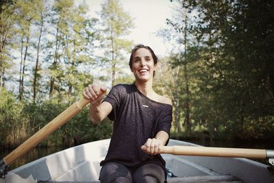 Mid adult woman rowing boat on river in forest