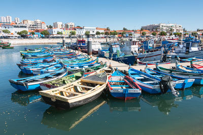 Boats moored in harbor against buildings in city