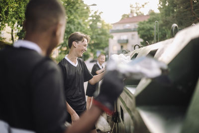 Happy boys putting plastic garbage bags in recycling bins