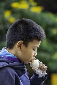Side view of boy eating food at outdoors