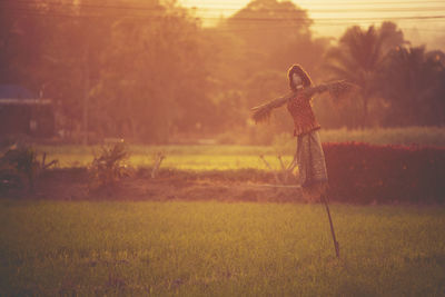 Scarecrow on field during sunset