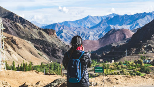 Rear view of man looking at mountains against sky