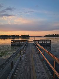 Dock over lake against sky during sunset
