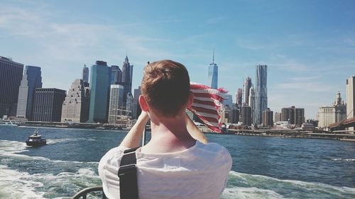 Rear view of man on ferry boat against city