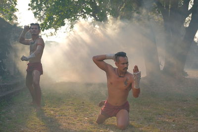 Full length of shirtless man standing on field