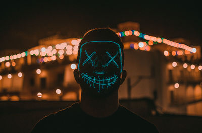 Portrait of man standing against illuminated city at night