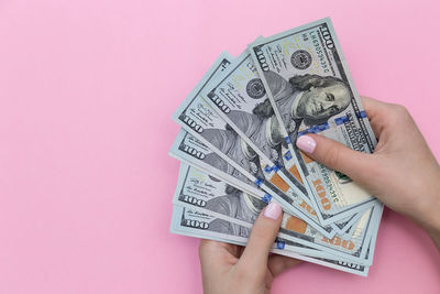 Close-up of hand holding paper against colored background