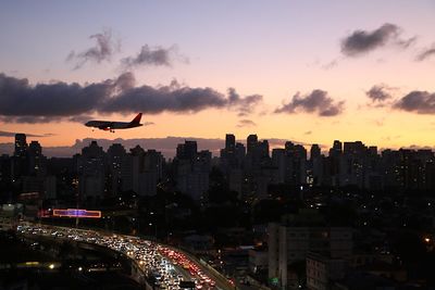 Aerial view of illuminated cityscape against sky during sunset