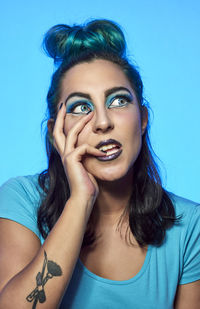 Portrait of beautiful young woman against blue background