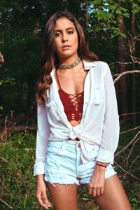 Portrait of beautiful young woman standing against plants