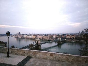 Bridge over river against cloudy sky