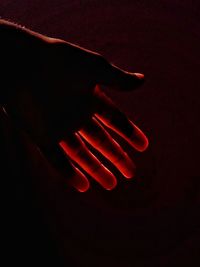 Close-up of human hand against illuminated background