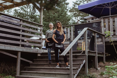 Full length portrait of smiling coworkers standing on steps in restaurant