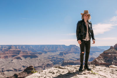 Man standing on rock against sky